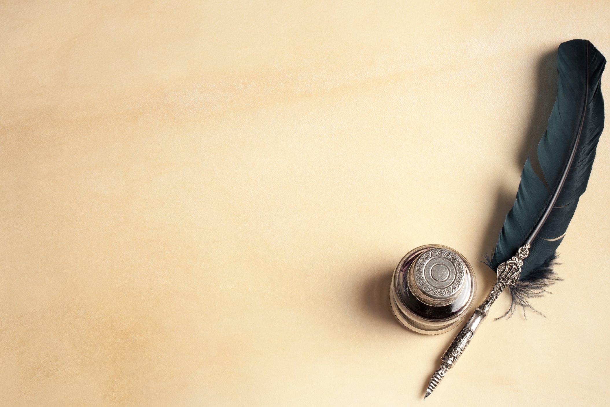 Image: a feather writing quill and metal embossed inkwell